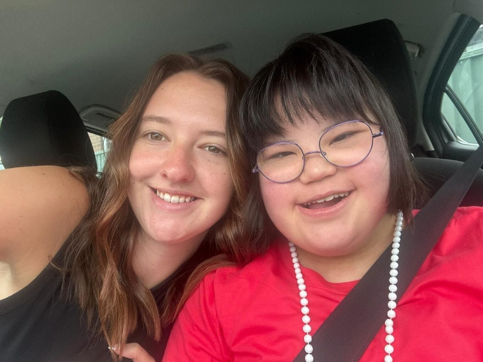 A Morhaven support worker and a member smiling together in a car on the way to an activity.