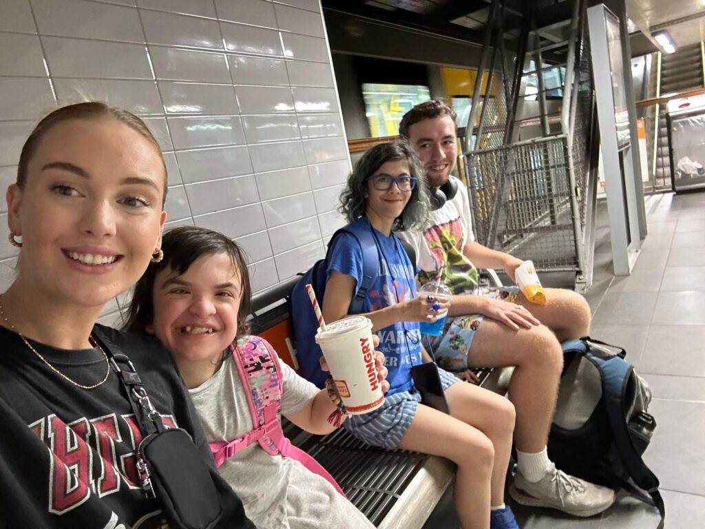Morhaven members and a support worker on a train station platform during a community outing.