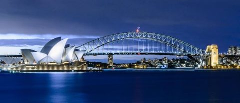 Sydney Harbour at dusk, with the Opera House and the Harbour Bridge lit up.