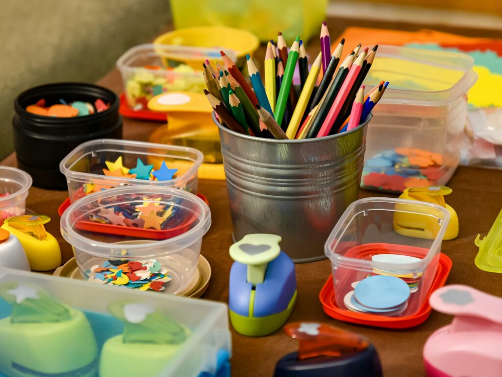 Coloured pencils and craft supplies laid out on a workshop table.